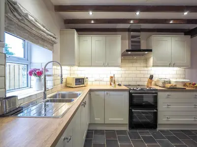 a kitchen with white cabinets and a sink at Bryndalis Aberaeron in Ciliau-Aeron
