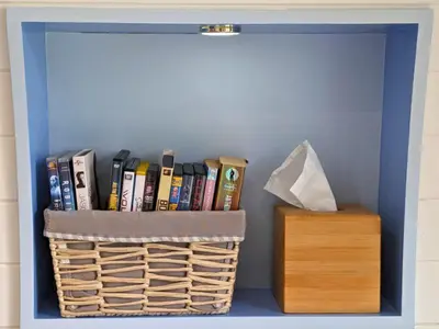 a book shelf with a basket and a box at The Kingfishers Burrow in Llandovery