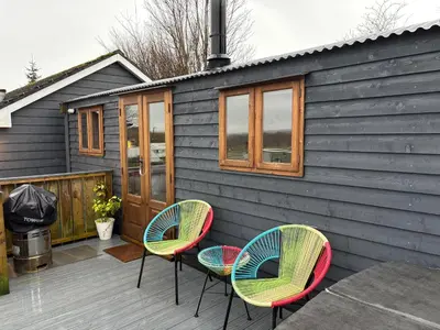 a patio with three chairs and a house at Hafod Shepherd Hut in Aberystwyth