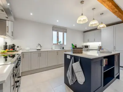 a kitchen with white cabinets and a blue island at Nupton Hop Kiln in Kings Pyon