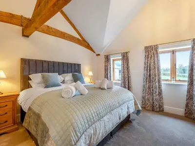 a bedroom with a large bed and two windows at Nupton Hop Kiln in Kings Pyon
