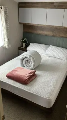 a large bed with white sheets and a pink pillow at Barmouthbay209 in Barmouth