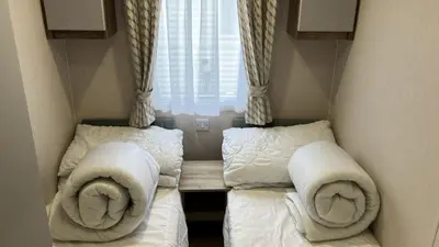 a small room with two beds and a window at Barmouthbay209 in Barmouth