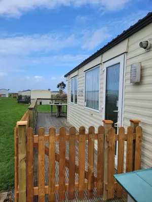 a wooden fence in front of a house at Cosy caravan Sunbeach in Llwyngwril