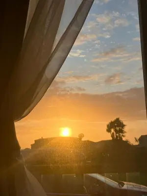 a sunset seen through a window with the sun setting at Cosy caravan Sunbeach in Llwyngwril