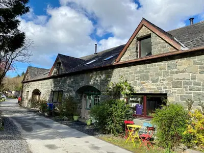 a stone house with chairs and tables in front of it at Ty'r Adar at Graig Wen in Arthog