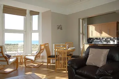 a living room with a couch and a table and chairs at Abermaw Sea View Apartment in Barmouth