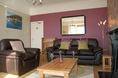 a living room with a leather couch and a coffee table at Abermaw Sea View Apartment in Barmouth