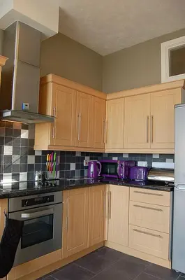 a kitchen with wooden cabinets and purple appliances at Abermaw Sea View Apartment in Barmouth