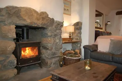 a stone fireplace in a living room with a stove at Ty Del - Beautiful Home in Tywyn in Tywyn