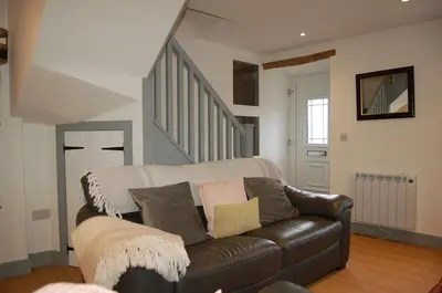 a living room with a leather couch and stairs at Ty Del - Beautiful Home in Tywyn in Tywyn