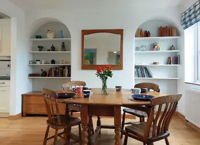 a dining room table with chairs and a mirror at Garreg Wen - White Stone, family holiday home in Barmouth