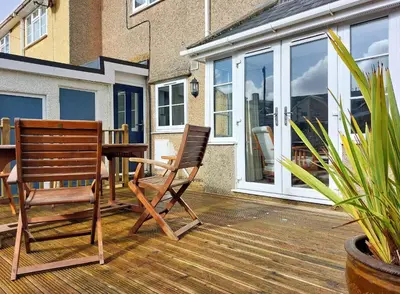 a patio with two chairs and a table on a deck at Garreg Wen - White Stone, family holiday home in Barmouth