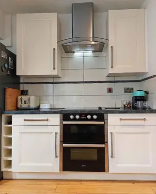 a kitchen with white cabinets and a stove top oven at Garreg Wen - White Stone, family holiday home in Barmouth