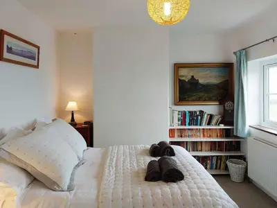 a bedroom with a white bed with shoes on it at Garreg Wen - White Stone, family holiday home in Barmouth