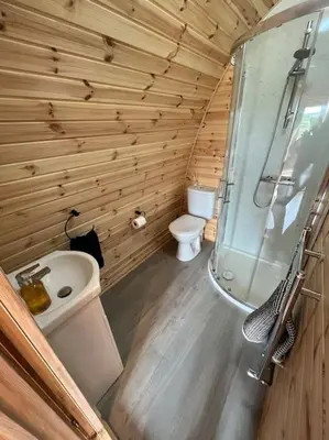a wooden bathroom with a toilet and a sink at The Pod Patch - Trelerney Pod in Bishops Castle