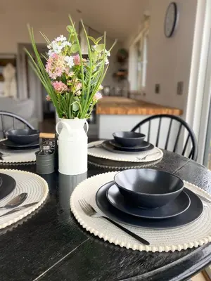 a black table with black plates and a vase with flowers at Glyndwr Way Cabin in Machynlleth