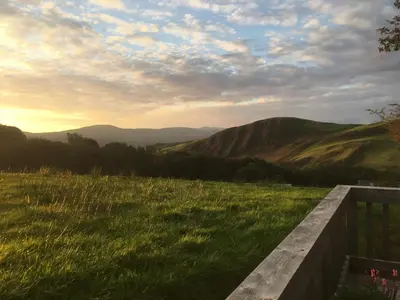 a bench in a field with mountains in the background at Glyndwr Way Cabin in Machynlleth