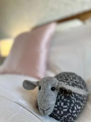 a stuffed sheep is laying on a bed at Glyndwr Way Cabin in Machynlleth