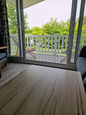a screened porch with a view of a deck at HARRIES LODGE QUAY WEST milkwood way in New Quay
