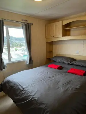 a bedroom with a large bed with red pillows on it at Seaside View Holiday Home in Aberystwyth