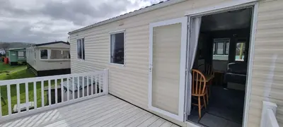 a mobile home with a deck with a sliding glass door at Seaside View Holiday Home in Aberystwyth