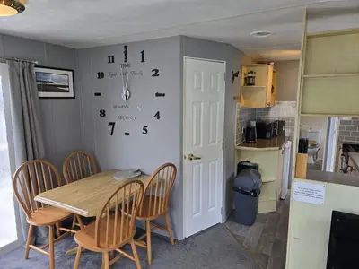 a dining room with a table and a clock on the wall at Seaside View Holiday Home in Aberystwyth