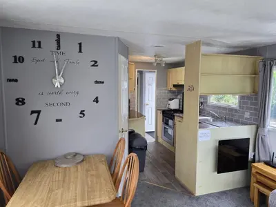 a kitchen with a table and a clock on the wall at Seaside View Holiday Home in Aberystwyth