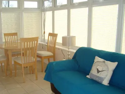 a living room with a blue couch and a table at Caerhafod Llangrannog in Llanllwchaiarn