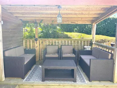 a pergola with two chairs and a table on a patio at Caerhafod Llangrannog in Llanllwchaiarn