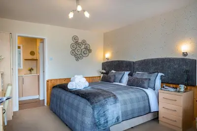 a bedroom with a large bed with a blue blanket at Estuary Lodge Motel in Talsarnau