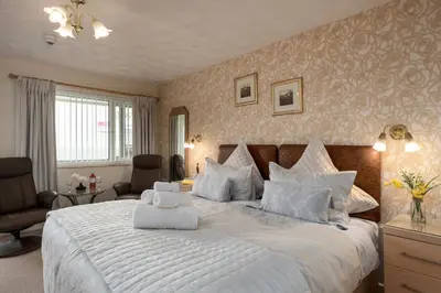 a bedroom with a large bed with white sheets at Estuary Lodge Motel in Talsarnau