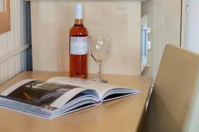 a bottle of wine and a book and a wine glass at Estuary Lodge Motel in Talsarnau