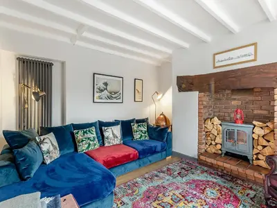 a living room with a blue couch and a fireplace at Dee Bank Cottage in Llangollen