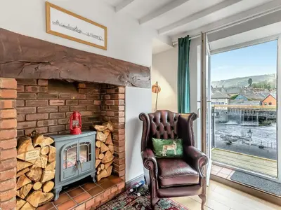 a living room with a chair and a fireplace at Dee Bank Cottage in Llangollen