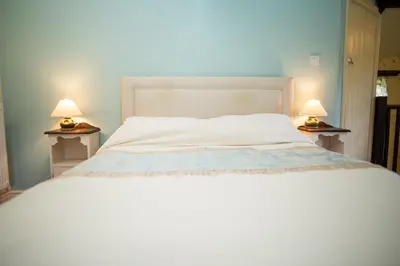 a bedroom with a white bed with two lamps at The Coach House New Quay in Cross Inn