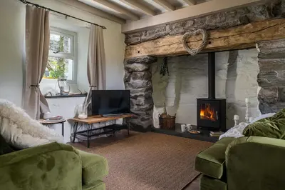a living room with a stone fireplace and a television at Pen-Y-Bryn Cottage in Blaenau-Ffestiniog