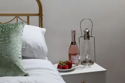 a bed with a bottle of wine and a plate of strawberries at Pen-Y-Bryn Cottage in Blaenau-Ffestiniog