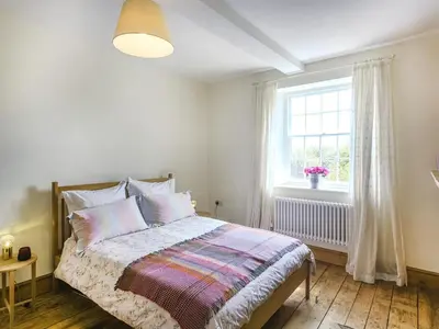 a white bedroom with a bed with a window at The Haven in Ludlow