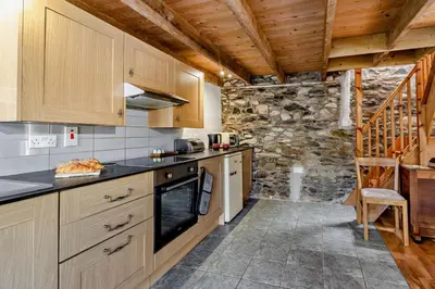 a kitchen with wooden cabinets and a stone wall at 2 Bed in Cross Inn oc-t29117 in Cross Inn