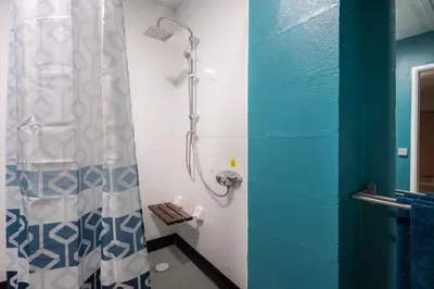 a shower in a bathroom with a blue and white shower curtain at Rural Group Lodging 19 rooms 83 beds Games room in Elerch