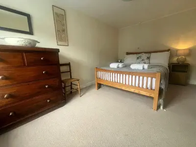 a bedroom with a bed and a wooden dresser at Nant Meigan, Georgian Townhouse in centre of Aberaeron, dog friendly in Aberaeron
