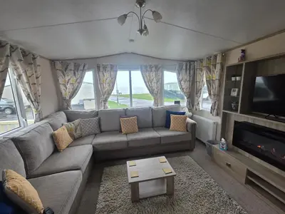 a living room with a couch and a tv at Bayview at Pengarreg in Llanrhystyd