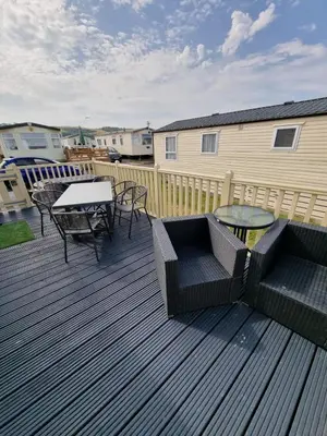 a deck with a table and two chairs and a table and a tablektop at Bayview at Pengarreg in Llanrhystyd