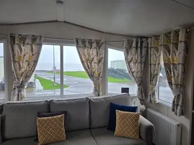 a living room with a couch and a large window at Bayview at Pengarreg in Llanrhystyd