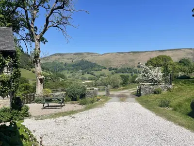 a gravel road with a bench and mountains in the background at Graig Las The Barn in Oswestry
