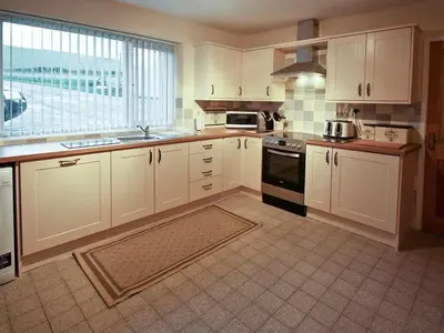 a kitchen with white cabinets and a stove top oven at Cob Cottage in Tregaron