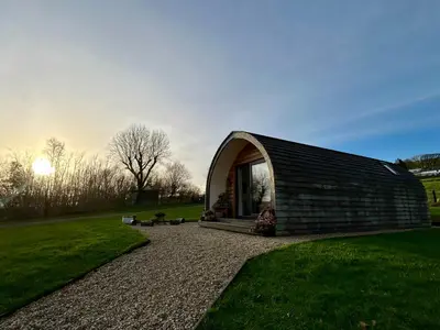 a small cabin in a grassy field with the sun setting at Willow in Llanidloes