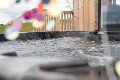 a pool of water in a yard with a wooden fence at Cae Bedw in Newtown