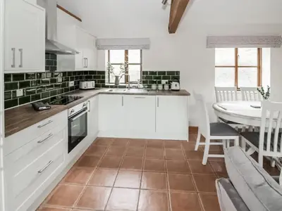 a kitchen with white cabinets and a table and a dining room at Uk46555 - Ragleth in Church Stretton